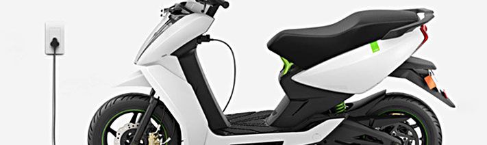 Side view of white electric scooter plugged into a power source.